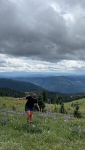 Midsize hiker balancing in wildflower field wearing Zorali Women’s Rugged Recycled Shorts